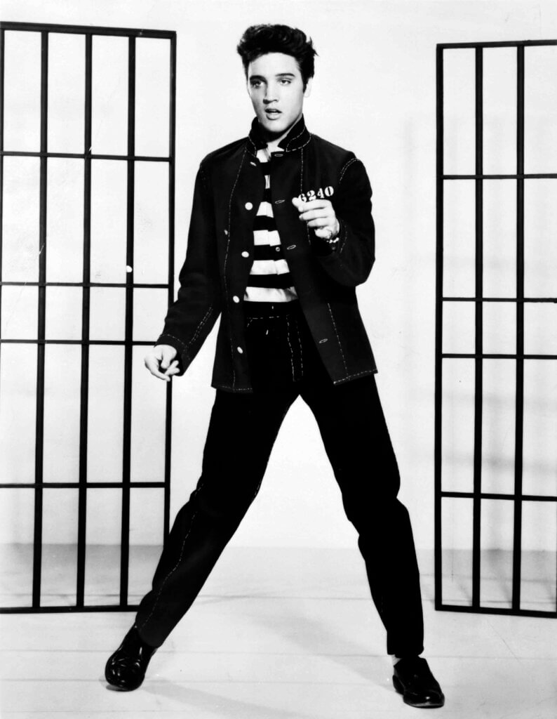 Elvis Presley in a dancing pose wearing a denim jacket